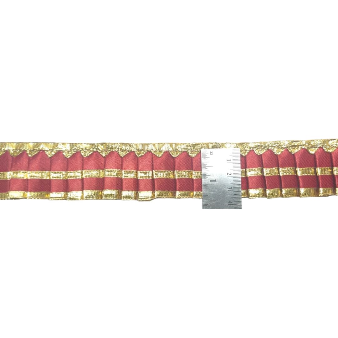 Red fabric with gold trim and a ruler for scale on a white background